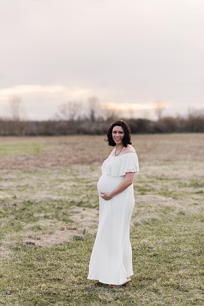 mom to be in white dress in green field at sunset
