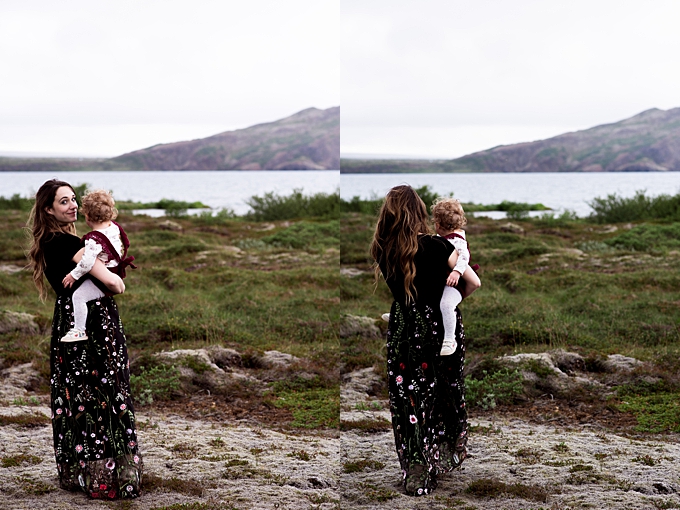 columbus family photographer mom holds daughter wearing black floral dress with lake and mountains in iceland