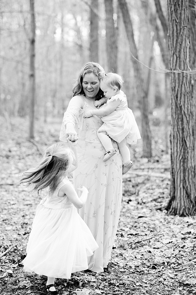 columbus family photographer black and white image of mom with two daughters twirling in the forest