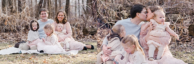 columbus family photographer mom and dad kiss and family of five sit in the forest