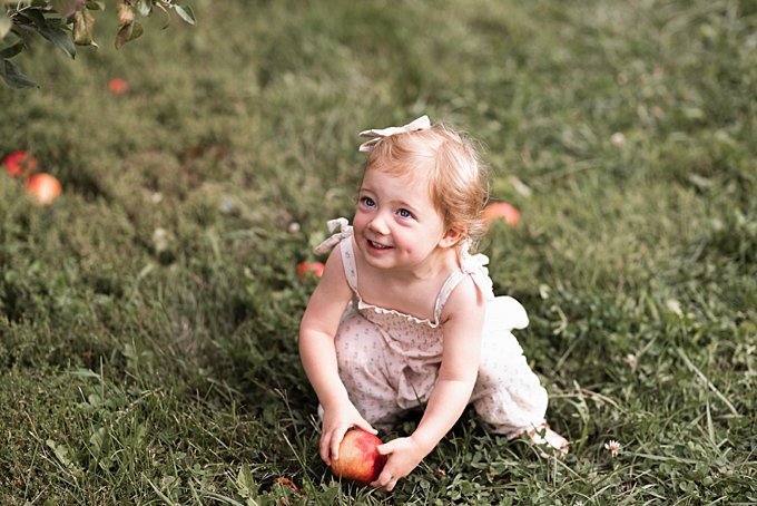 columbus baby photography baby holding apple in orchard wearing ivory jumper