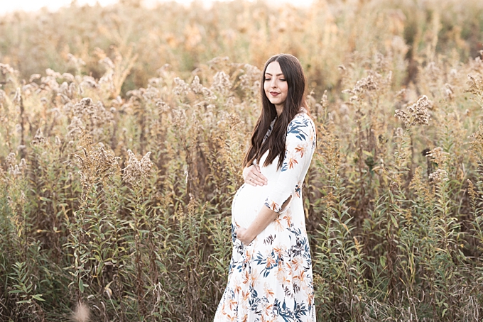 pregnant mom holds belly in field