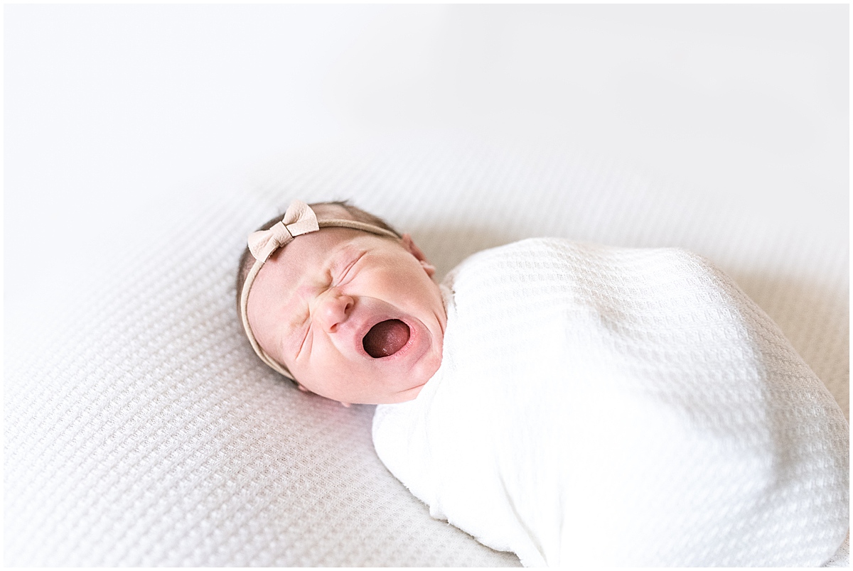 lifestyle newborn photography baby girl wearing bow yawns