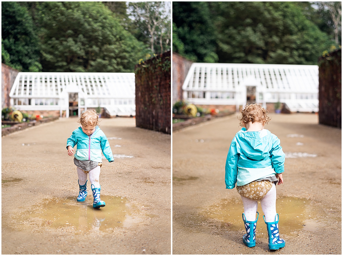 lifestyle photographer toddler splashes in puddle with blue rainboots