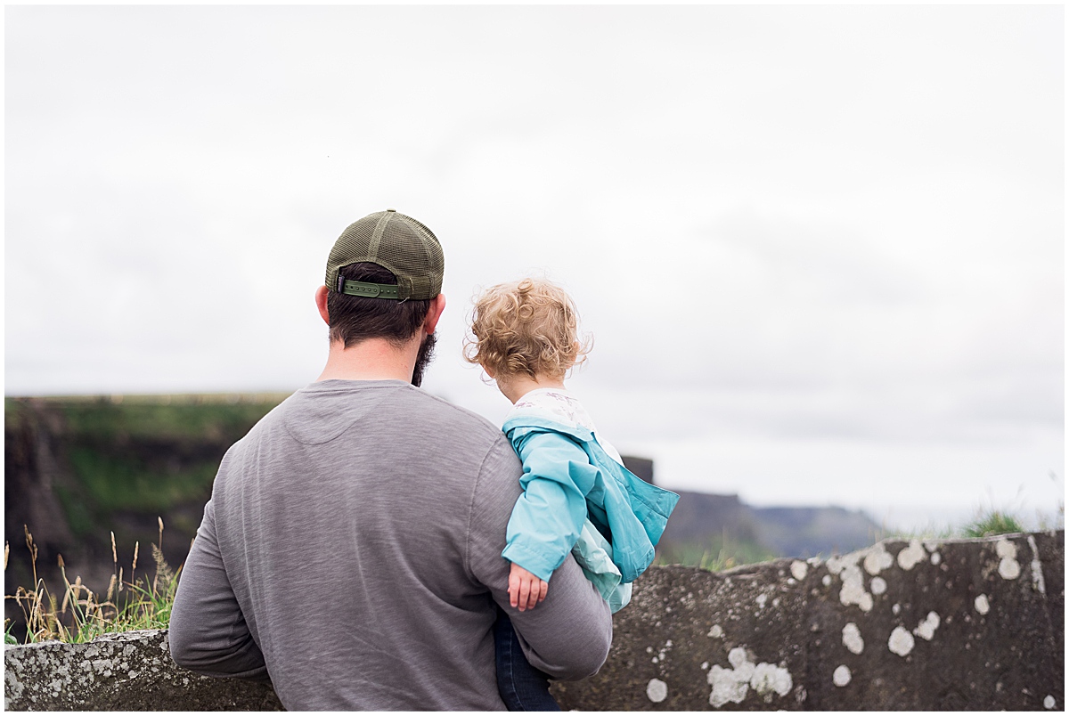 lifestyle photographer dad holds toddler at the cliffs of moher