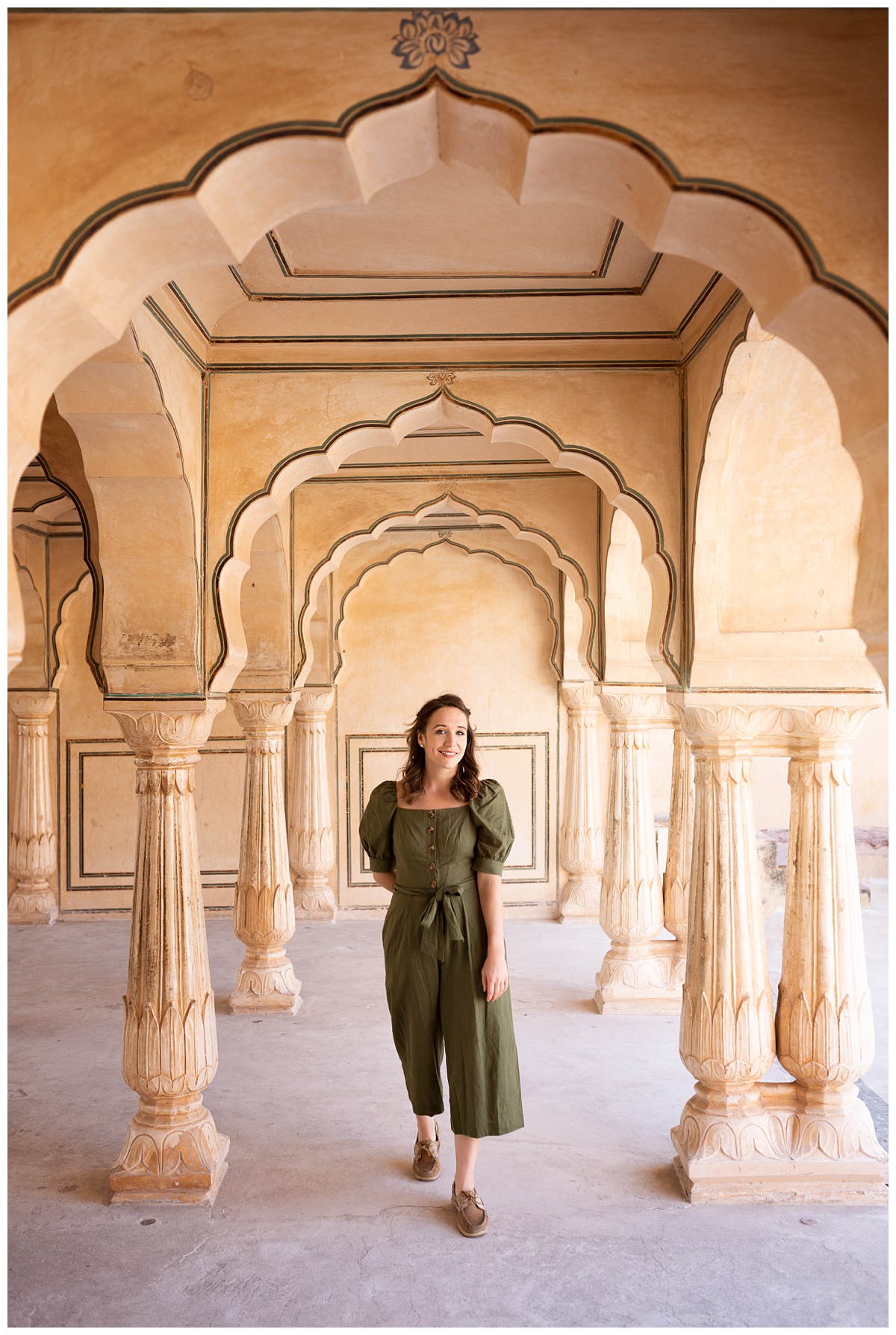 ohio lifestyle photographer stands in yellow archways in amer fort