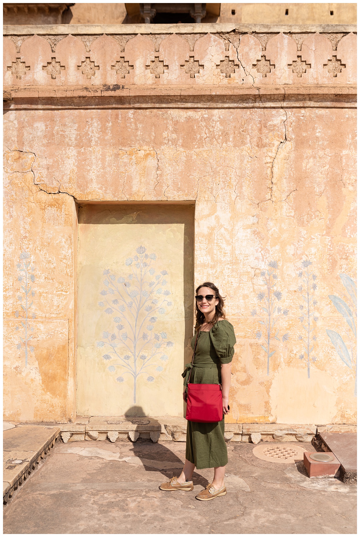 photographer stands in amer fort painted walls