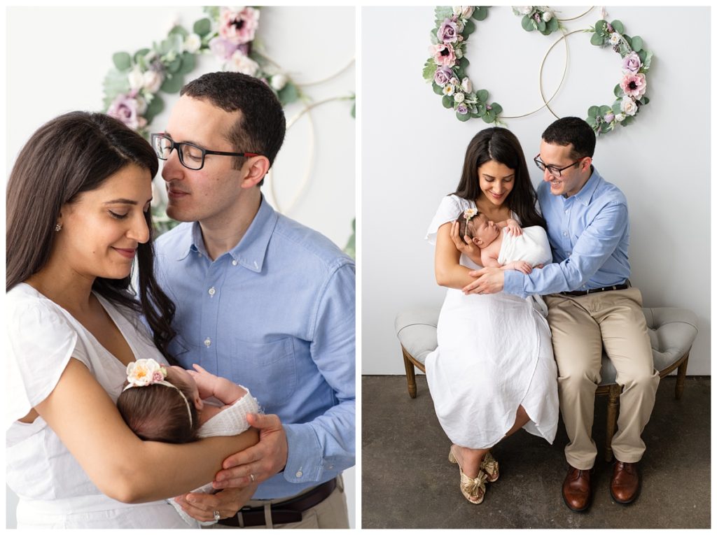 mom in white dress and dad in blue shirt cradle newborn baby girl in studio