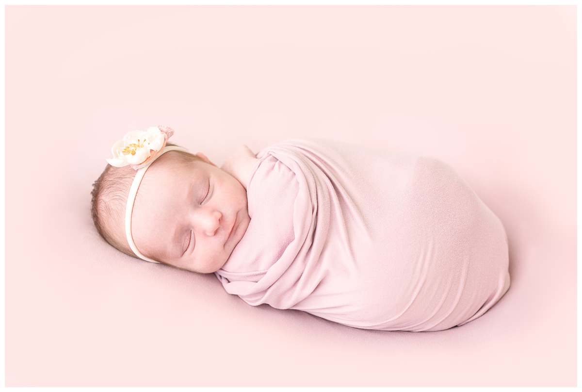 newborn girl with floral headband sleeps