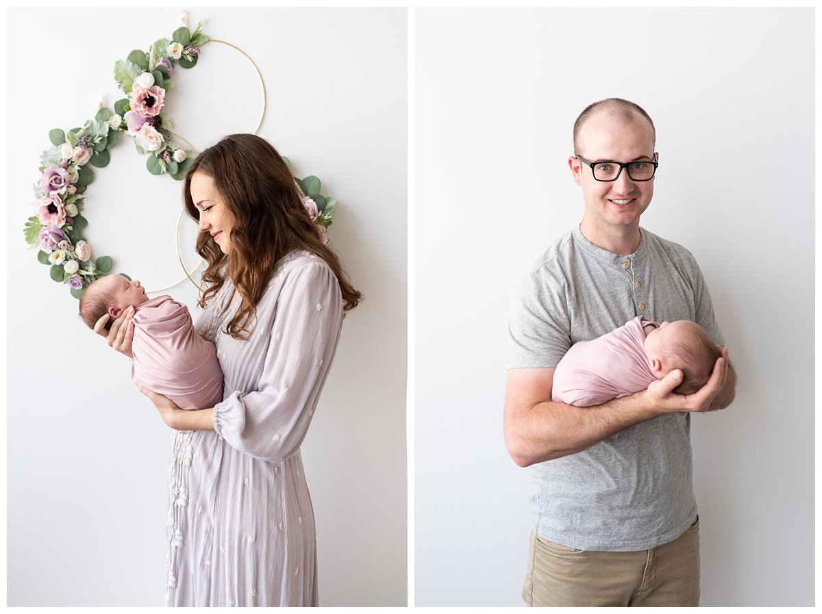 mom smiles at newborn girl in studio behind floral backdrop