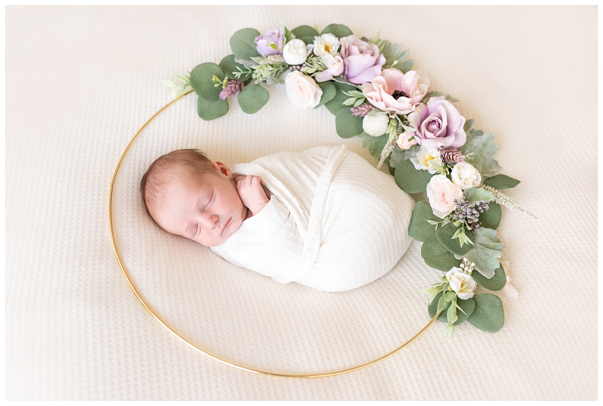 newborn girl sleeps in wreath of flowers