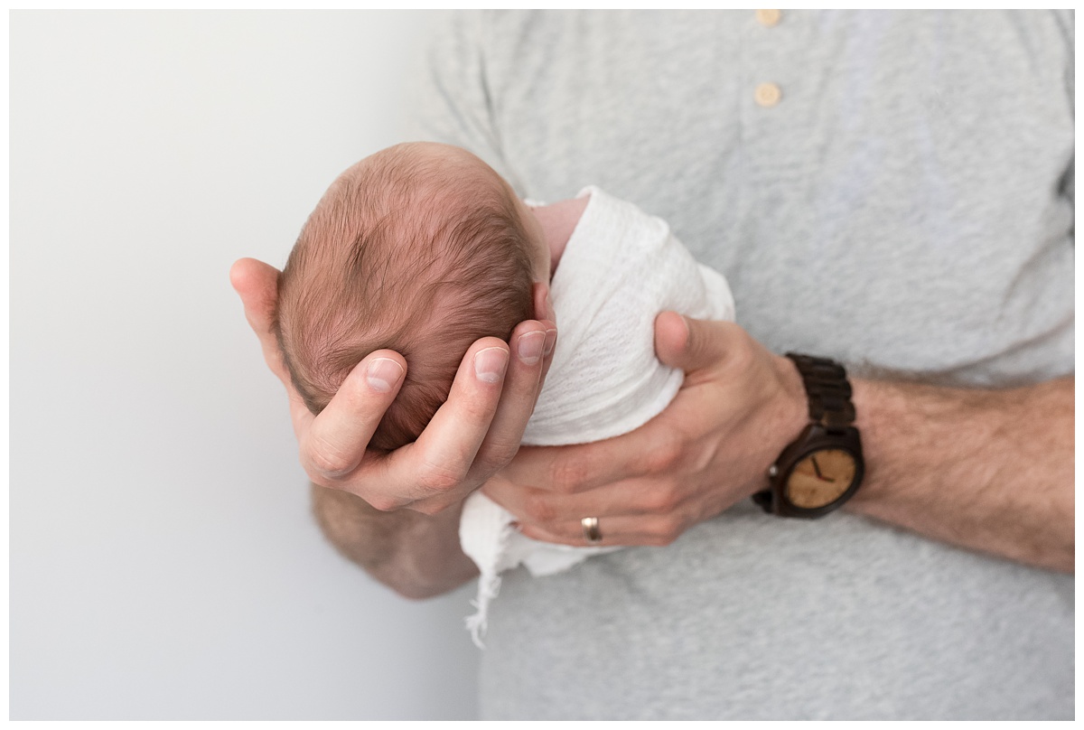 newborn cradled in dads hands