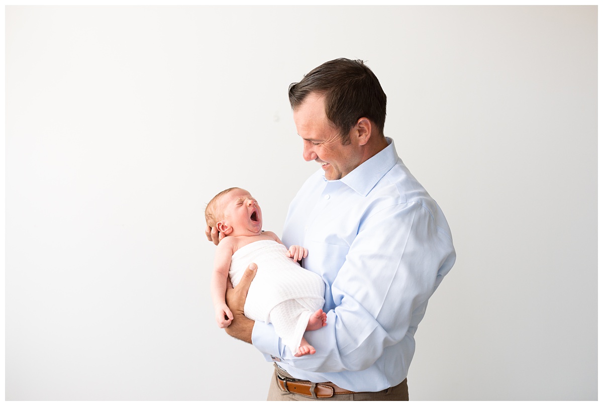 baby yawns in dad's arms blue studio newborn session columbus