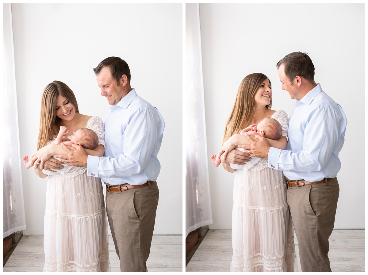 mom and dad look at each other holding son in studio newborn session columbus