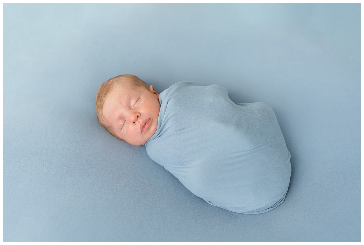 baby wrapped in dusty blue sleeps in studio newborn session columbus