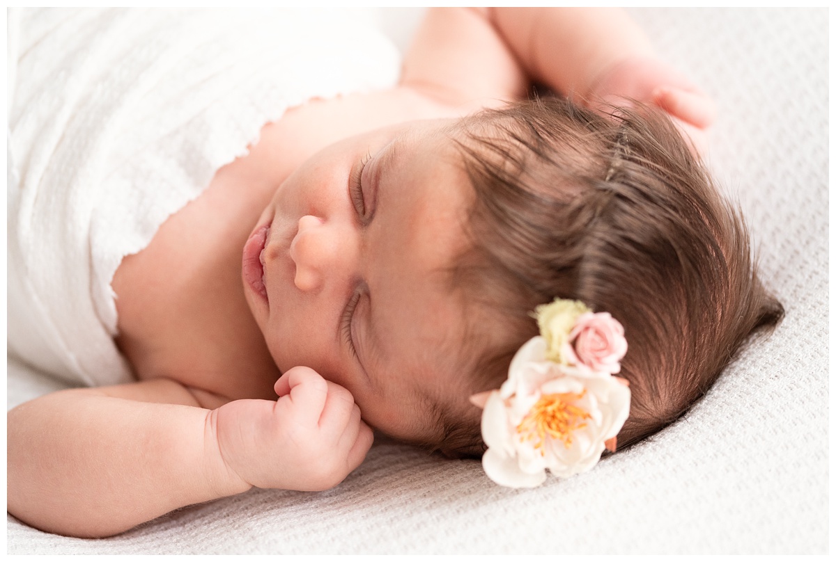 Top Newborn Photographer Columbus Ohio newborn wrapped in white with pink floral headband sleeps