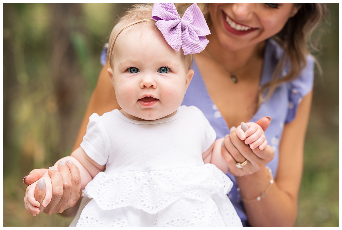 Top family Photographer Columbus Ohio toddler girl in white dress and purple bow stands with mom