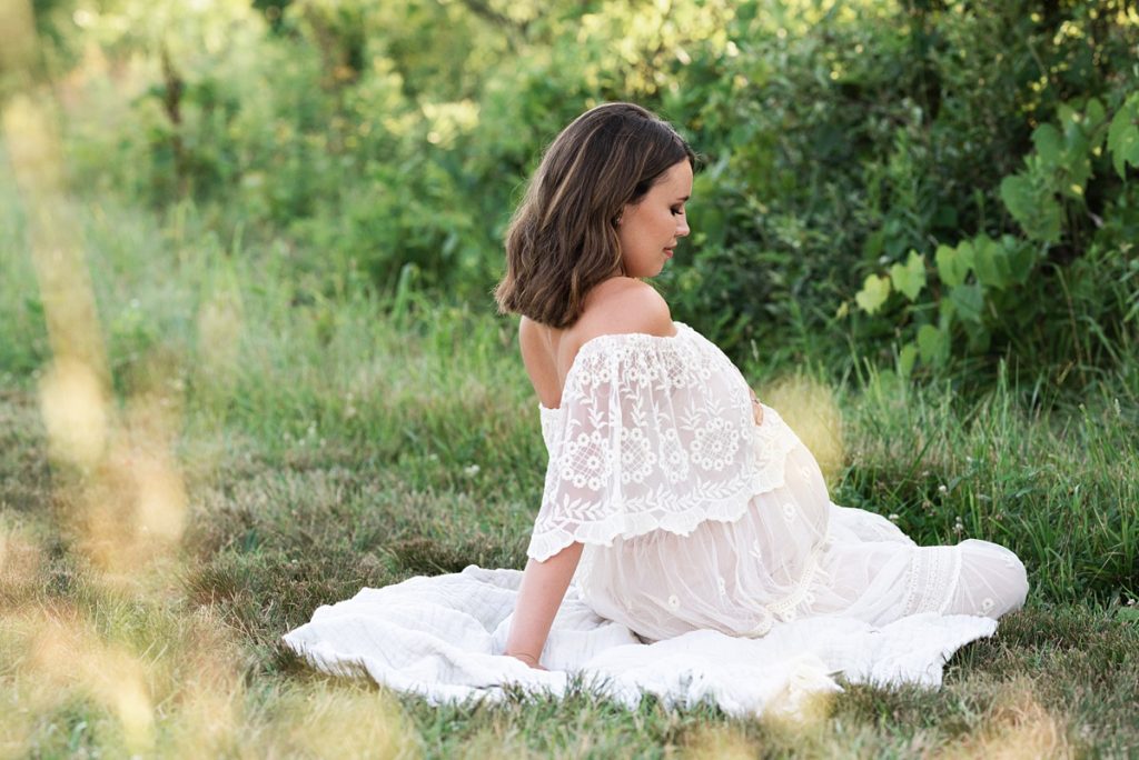 maternity photography columbus ohio mom sits in boho lace dress in field at sunset