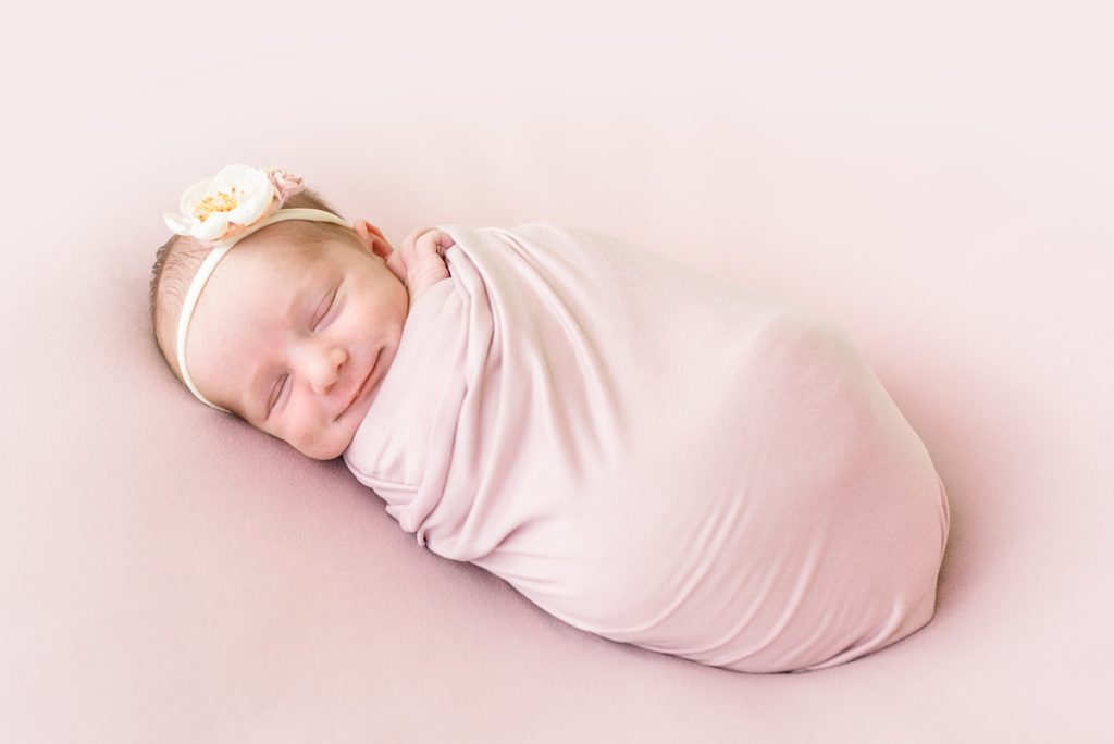 columbus ohio newborn photographer newborn girl smiles wrapped in dusty pink