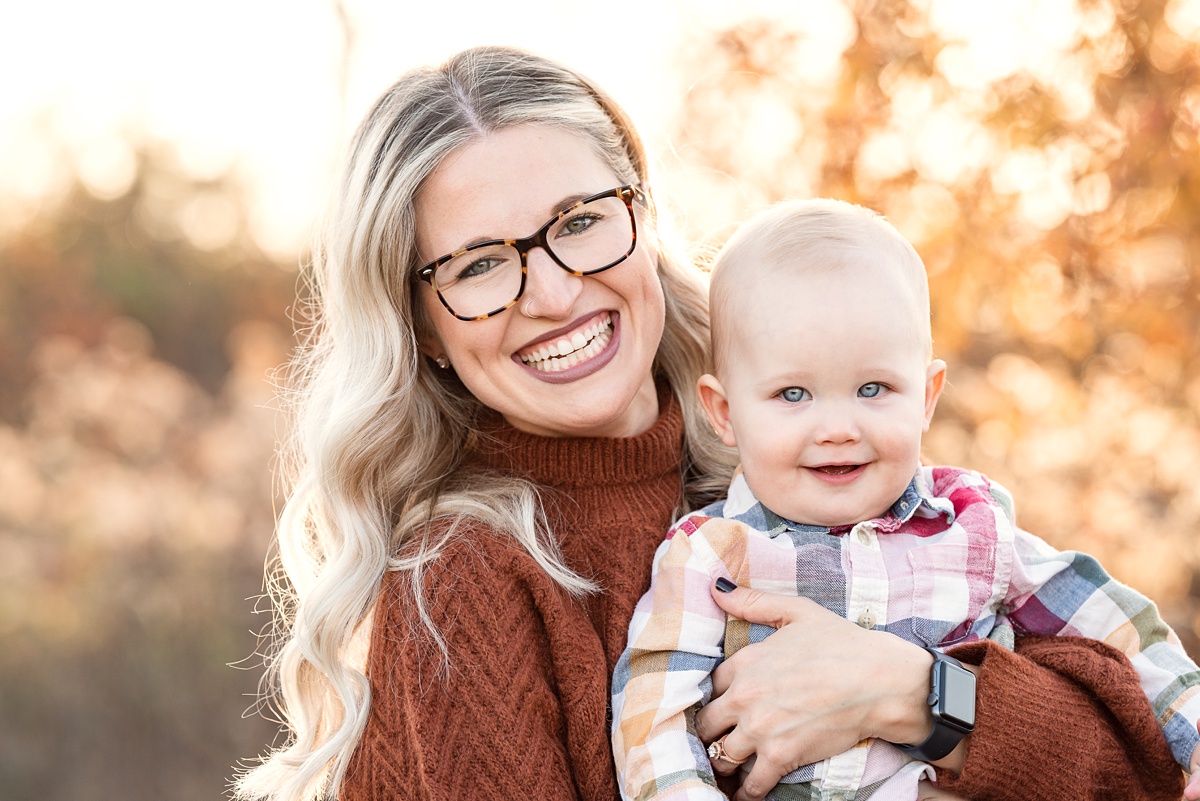 mom and baby boy smile outdoors in golden light in field