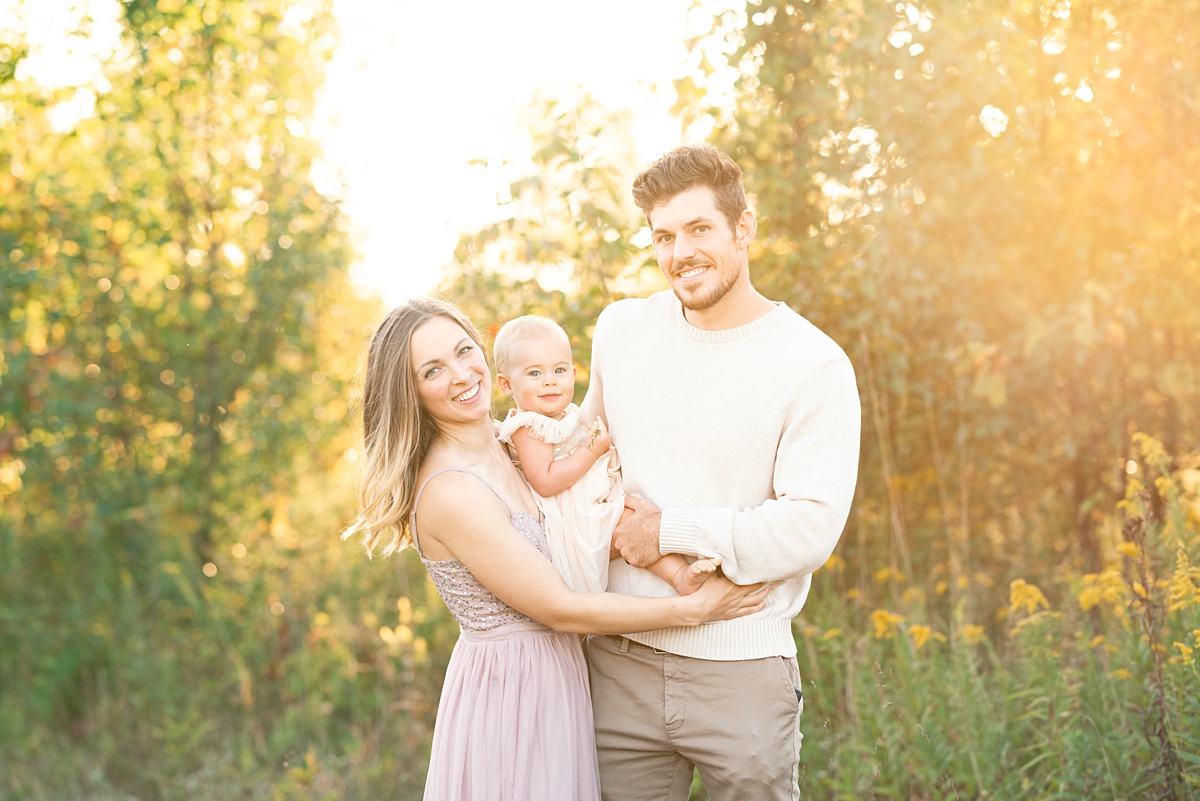 mom and dad hold toddler at golden hour columbus family photographer