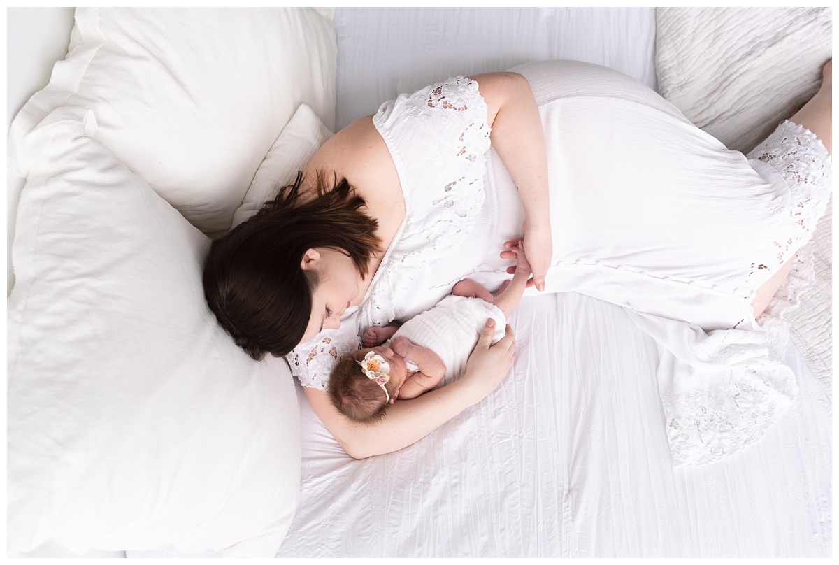Lifestyle Newborn Photographer Columbus Ohio mom and newborn daughter cuddle on bed