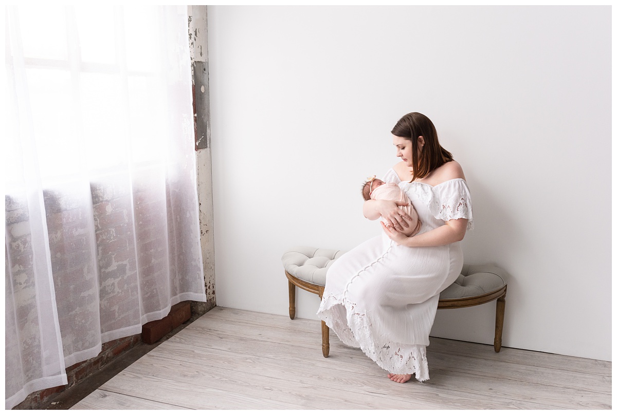Lifestyle Newborn Photographer Columbus Ohio mom holds newborn on bench in studio
