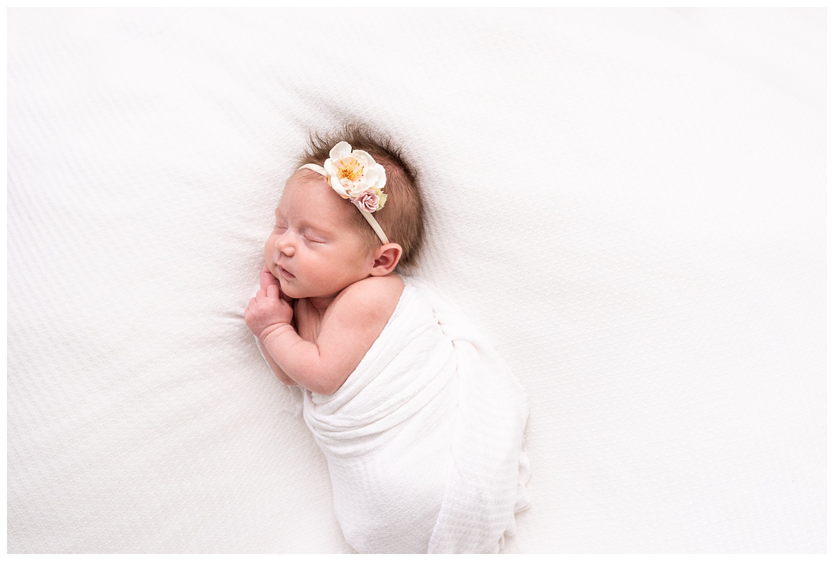 Lifestyle Newborn Photographer Columbus Ohio newborn gently wrapped sleeps on white background