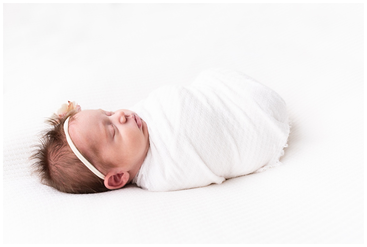 Lifestyle Newborn Photographer Columbus Ohio newborn wrapped in white sleeps on while blanket