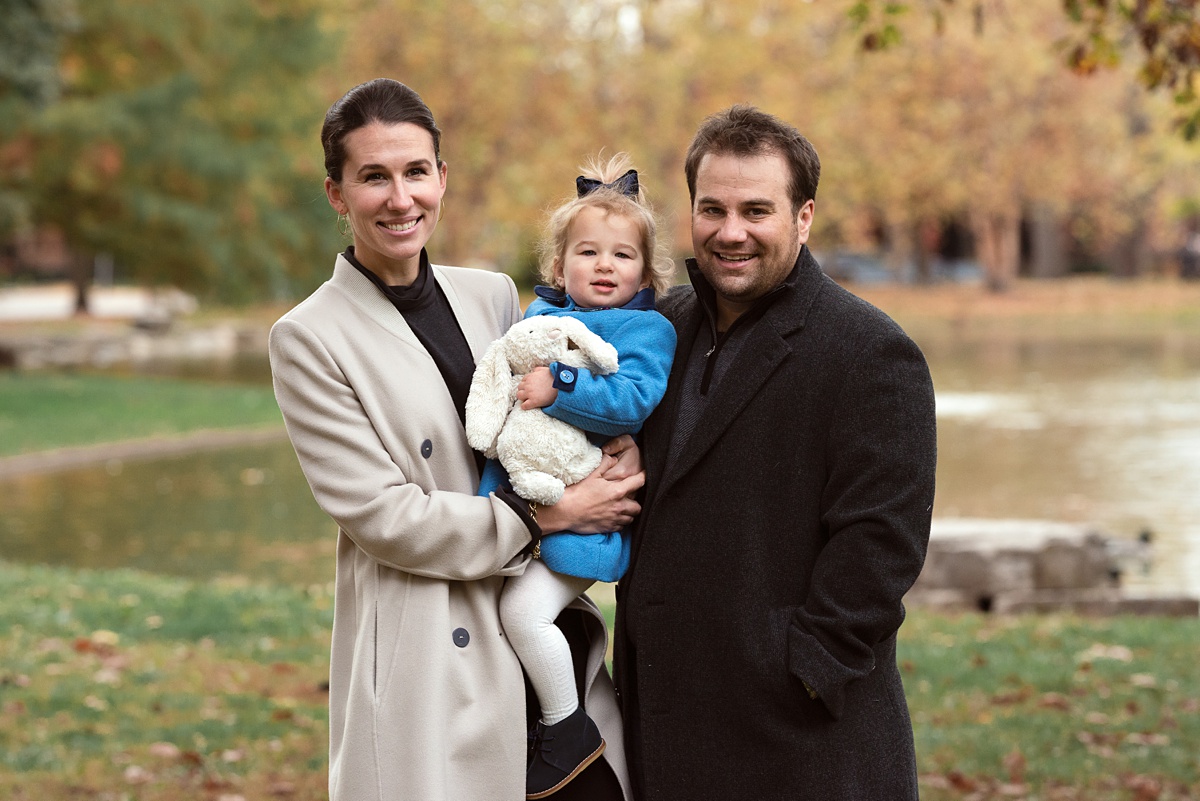 family of three poses in schiller park in jackets
