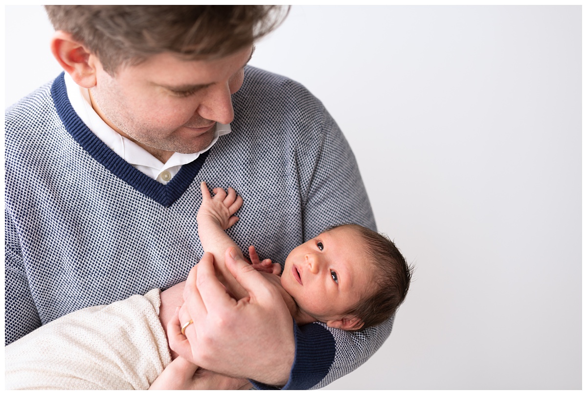 Best Columbus Newborn Photographer dad in blue sweater holds newborn boy 