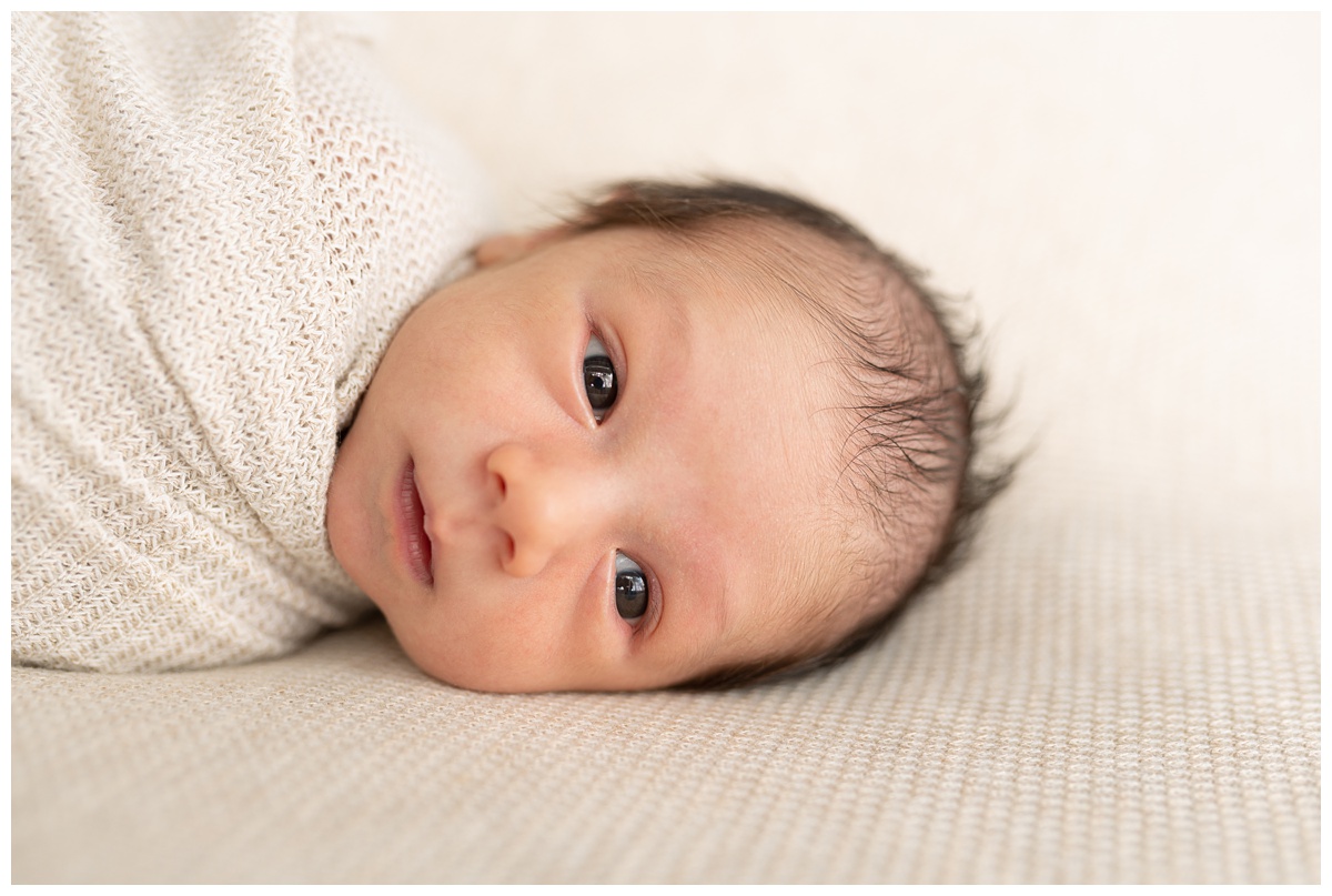 Best Columbus Newborn Photographer baby boy wrapped in tan waffle knit looks at camera