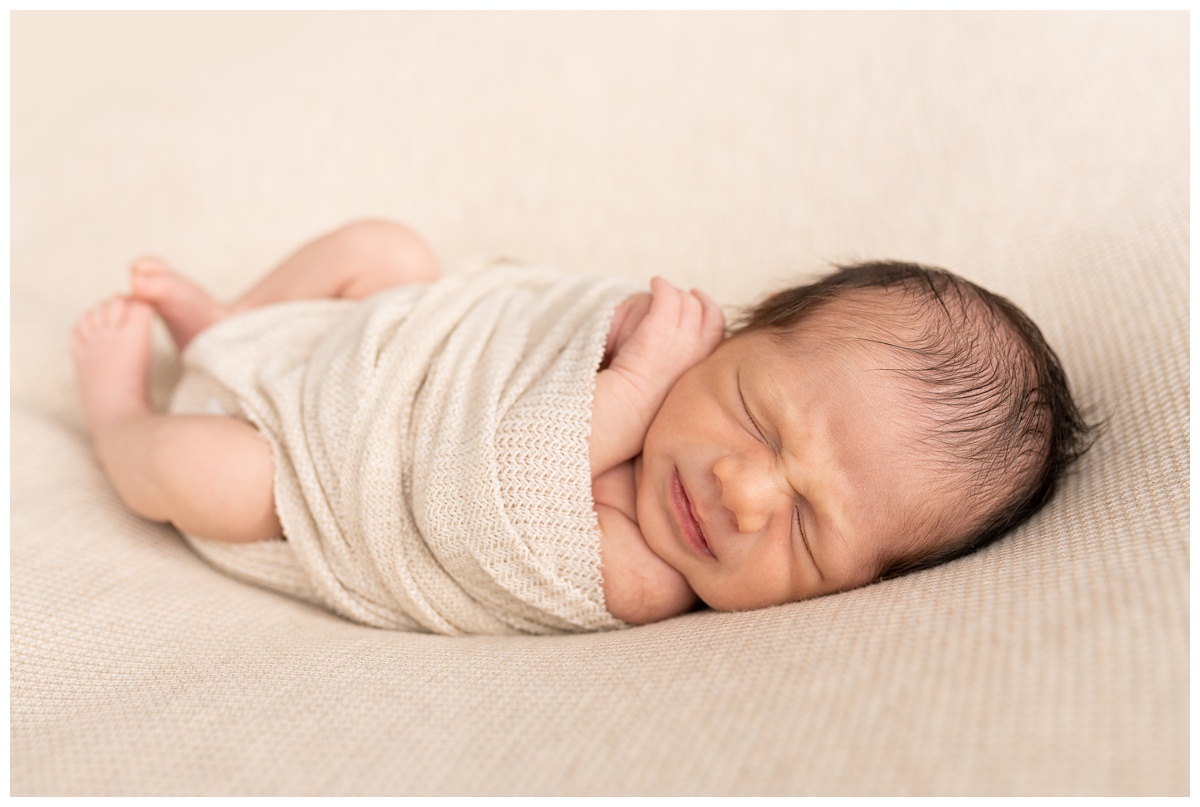 Best Columbus Newborn Photographer baby boy dreams with sad face with tan background