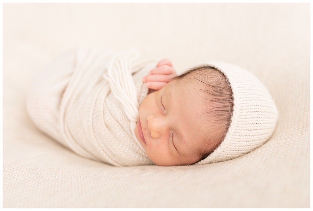 Best Columbus Newborn Photographer sleeping newborn with cream background and bonnet