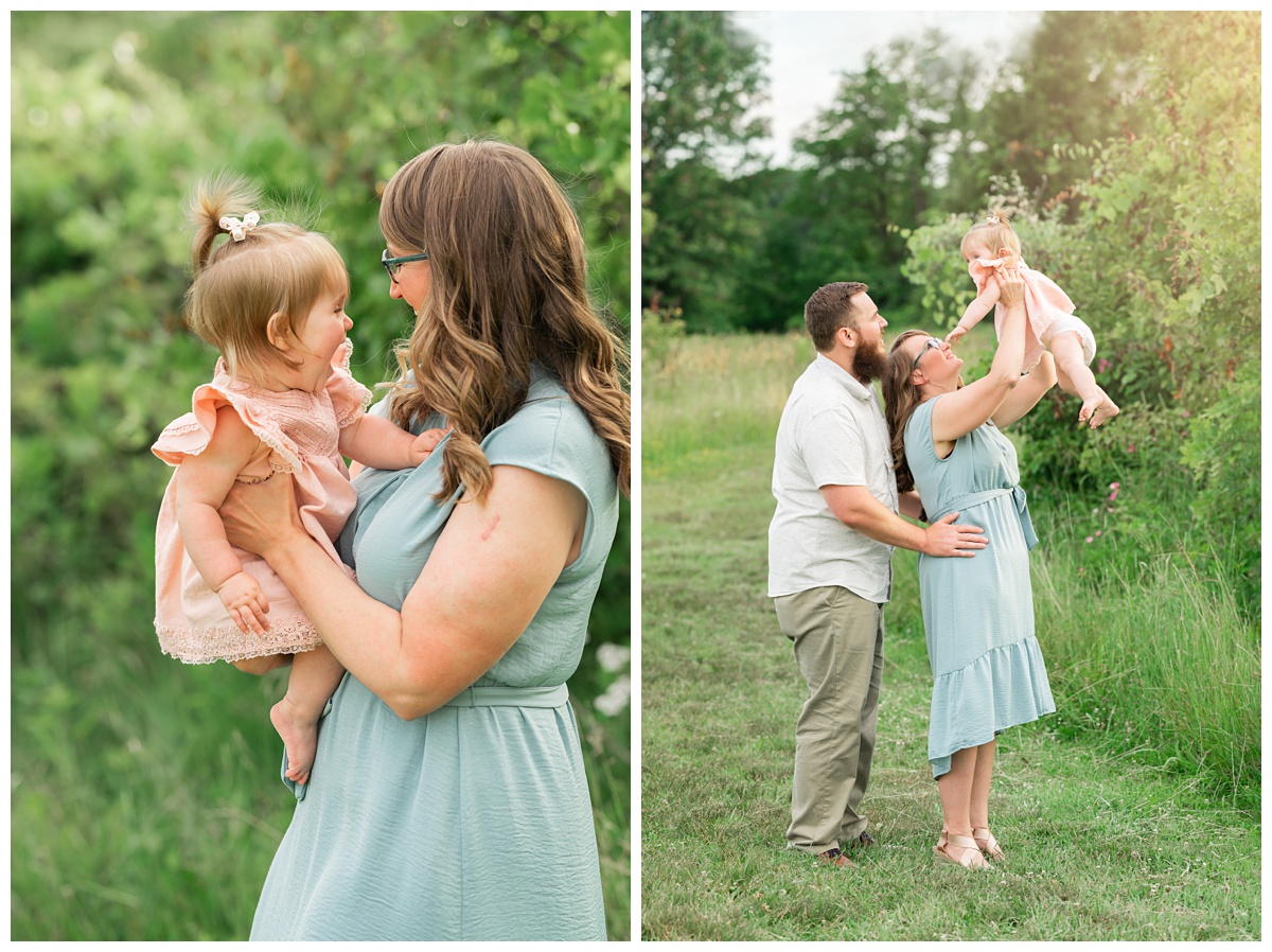 Family Photographers Columbus mom in blue dress holds up baby girl in pink dress outside 