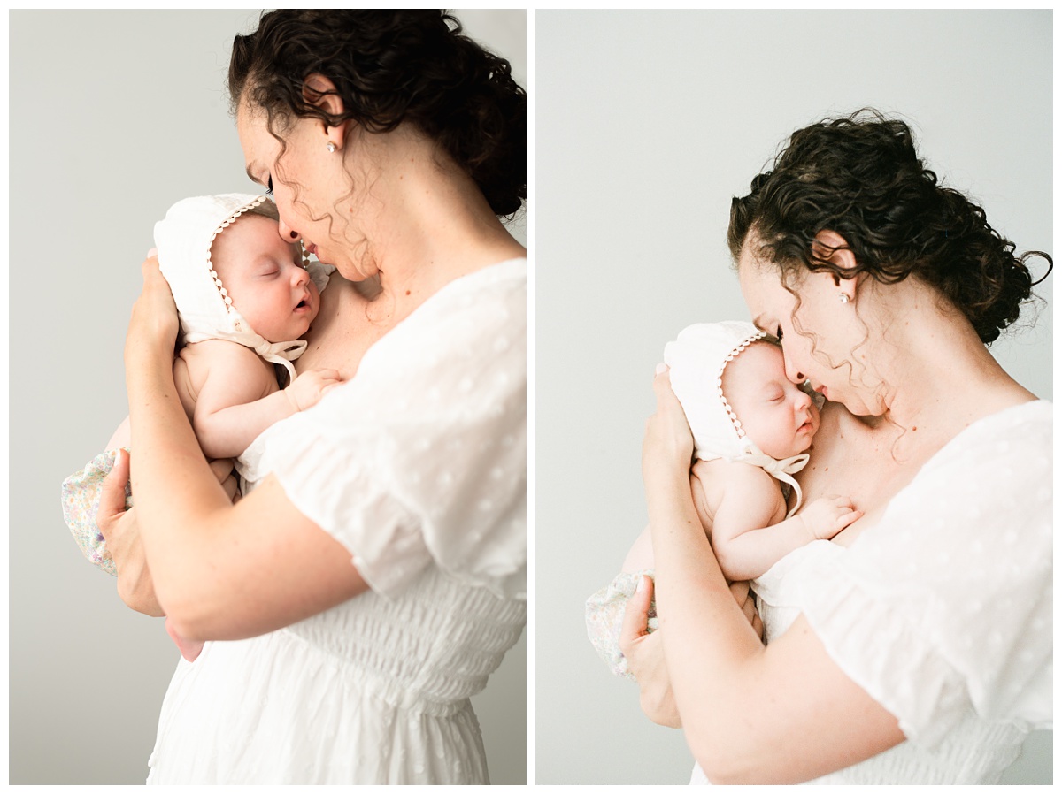 Best Columbus Ohio Baby Photographer mom in white dress snuggles sleeping baby in white bonnet 