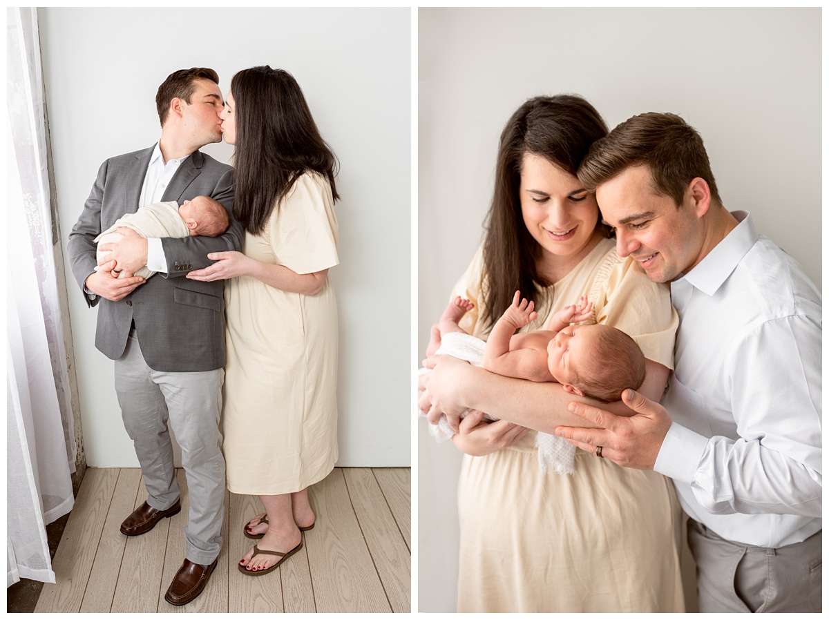 Top Columbus Ohio Newborn Photographer mom and dad kiss holding newborn boy in tan wrap