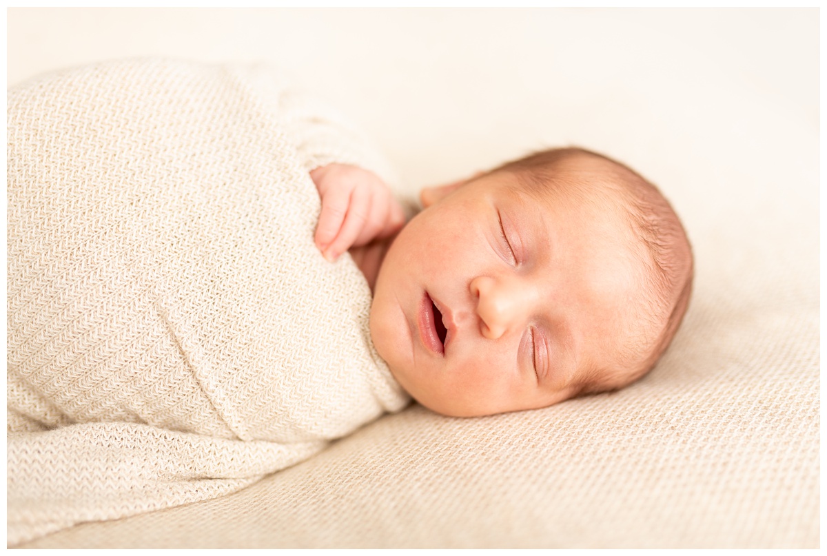 Top Columbus Ohio Newborn Photographer newborn boy sleeps in tan wrap with hand out