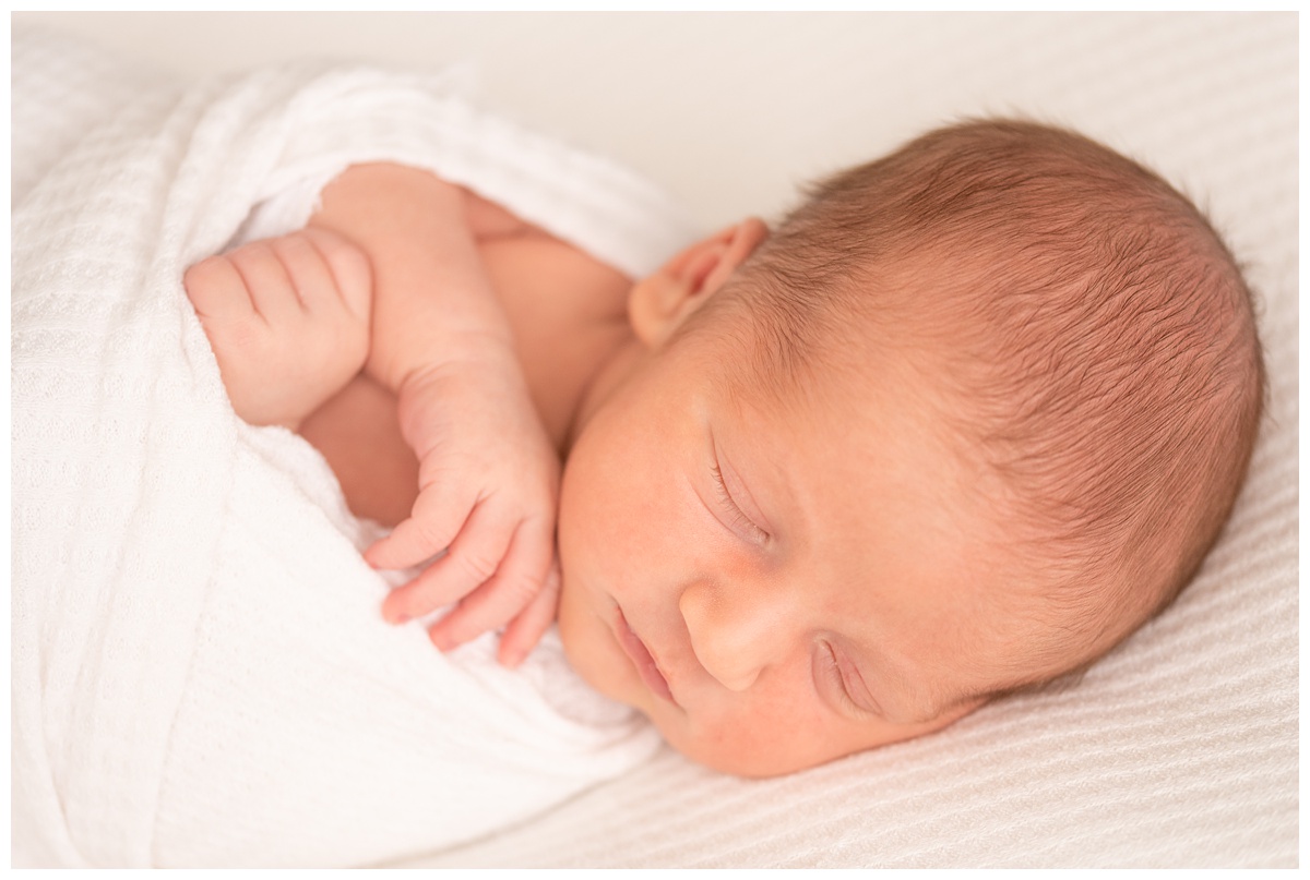 Top Columbus Ohio Newborn Photographer portrait of newborn boy with arms crossed sleeping in white waffle wrap