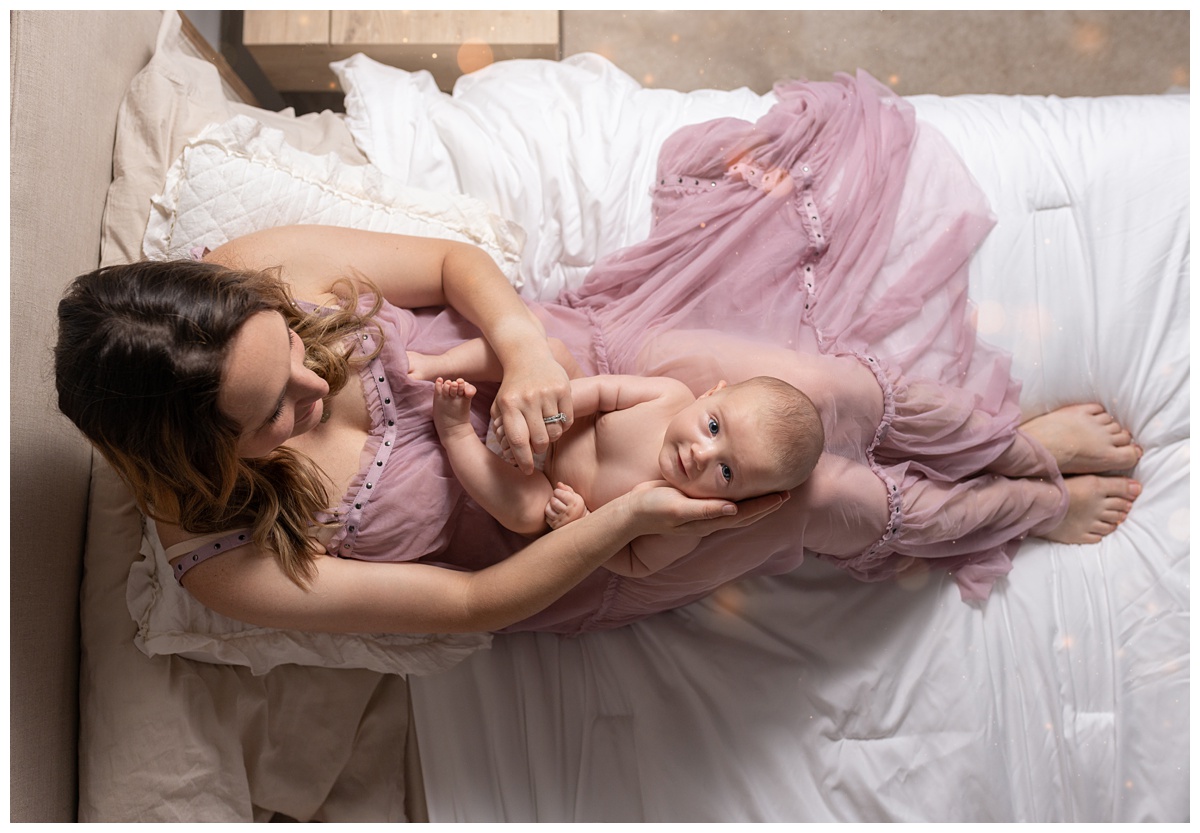 Columbus Lifestyle Newborn Photographer mother sits with newborn in purple dress on white sheets