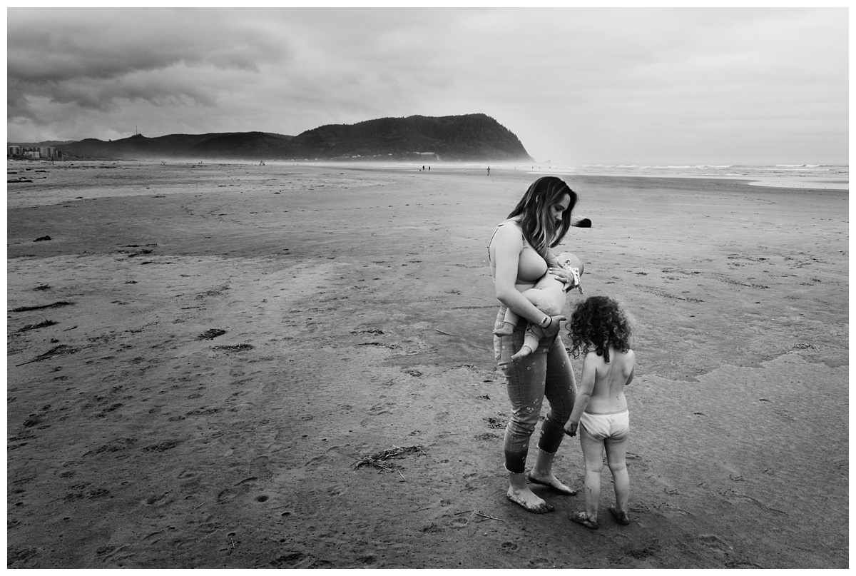 Columbus Lifestyle Travel Photographer mother breast feeds baby with young daughter nearby on beach