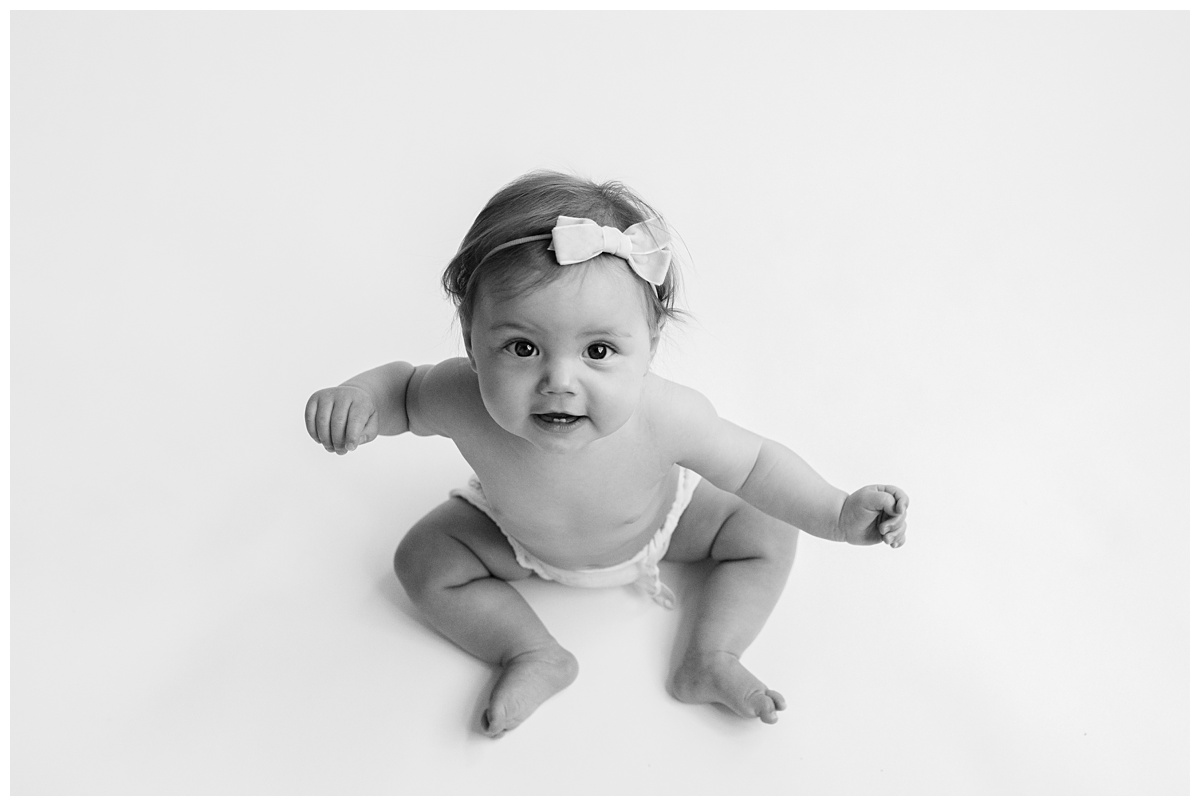 Classic Baby Portrait Photographer Columbus Ohio baby girl sits and looks up at camera in black and white