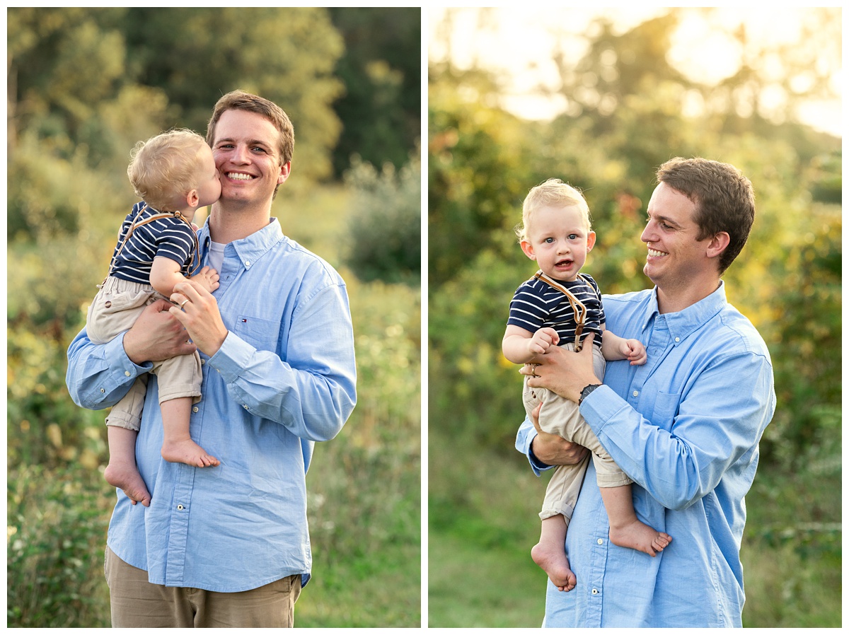 blond baby boy kisses dad holding him in field at sunset