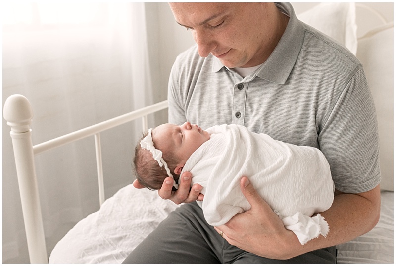 new dad holding baby girl in white wrap